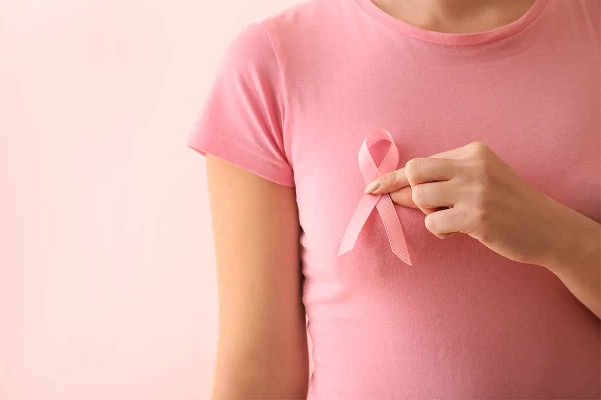 Ruban rose tenu sur un t-shirt, symbole de prévention du cancer du sein.