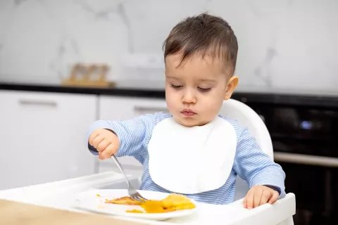 bébé qui mange tout seul à table